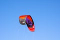 The image of `Best` Kitesurfing sport brand, the kite is in Red, Black and purple flying on the blue sky. Royalty Free Stock Photo